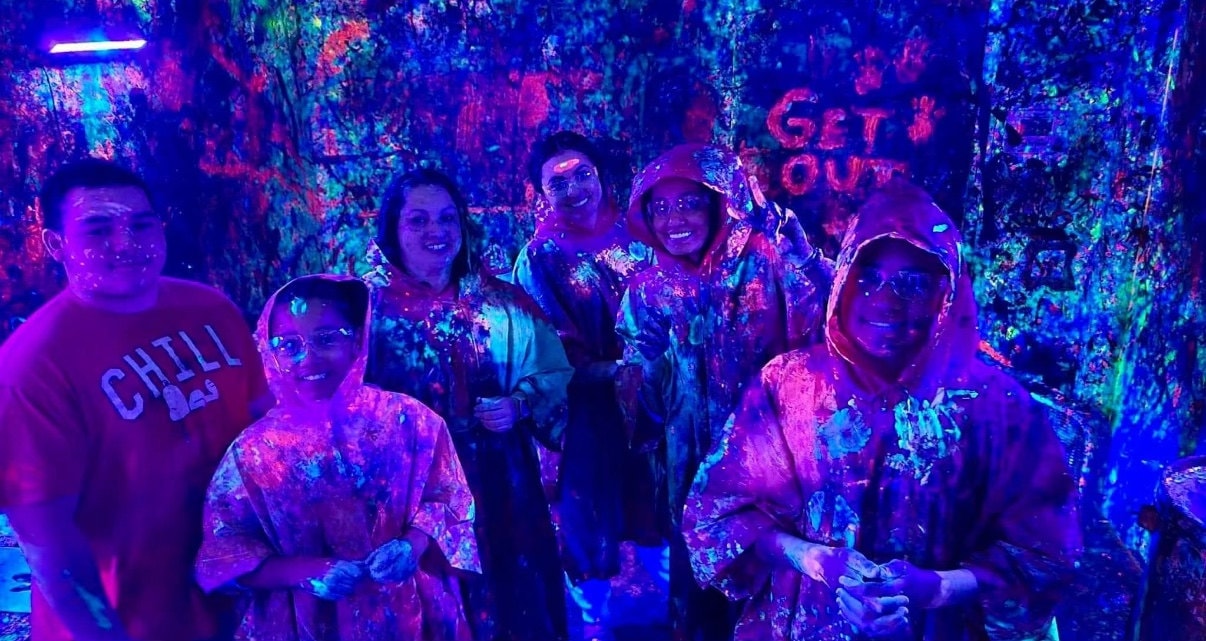 Group of guests throwing neon paint inside Splatter Room Iowa Des Moines